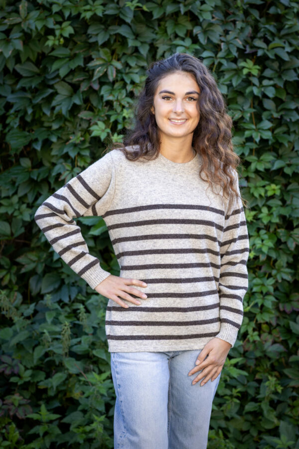 Jeune femme en promenade automnale avec le Pull Clun marron burel, écharpe légère et jean brut.