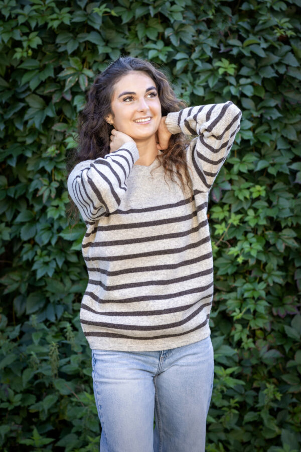 Femme élégante portant le Pull Clun beige rayé marron, associée à une jupe longue fluide.