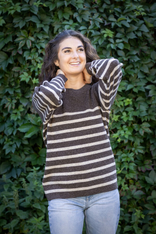 Femme souriante en intérieur, Pull Clun marron rayé beige, posé sur les épaules façon casual.
