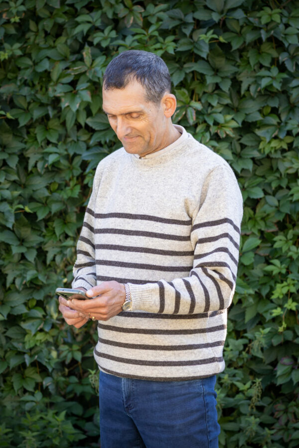 Homme portant le Pull Clun marron burel rayé beige, en balade à la campagne.
